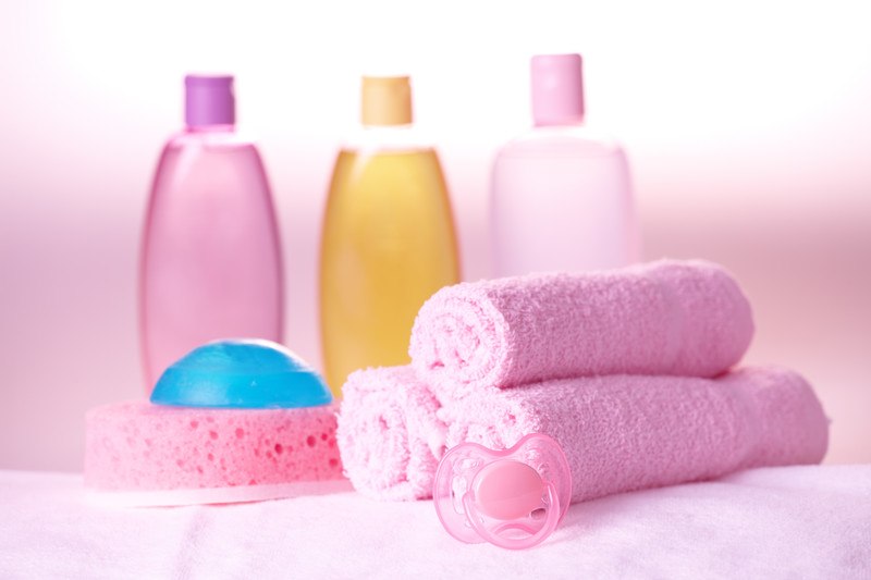 This photo shows a set of baby bath products and a set of three pink wash cloths with a soft pink background, representing the best kids affiliate programs.