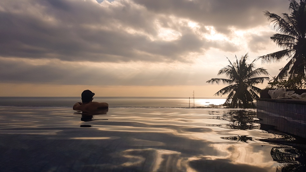 luxury lifestyle man on edge of infinity pool on rooftop