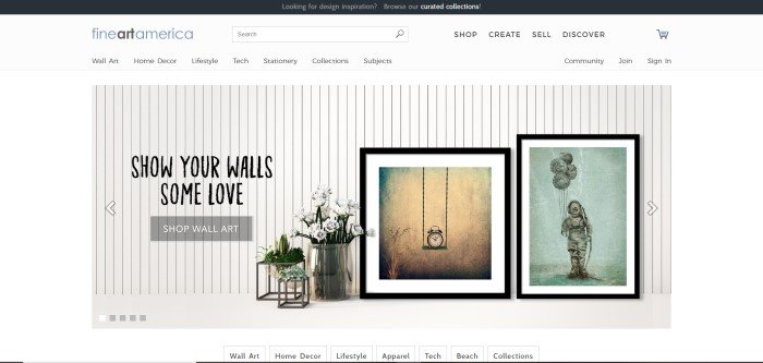 This screenshot of the home page for Fine Art America has a black header, white navigation bar, white background, and a photo of a white wood-paneled wall with several pieces of fine art leaning against it, along with a large silver vase of white flowers and a call-to-action button for shopping for wall art.