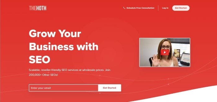 This screenshot of home page for The Hoth has a red background, white lettering inviting customers to grow their business with SEO , and an insert of a video clip with a smiling woman waving at the camera.