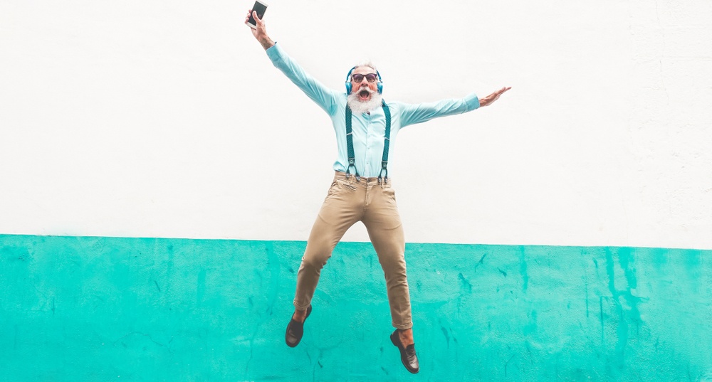 senior man jumping on colorful wall