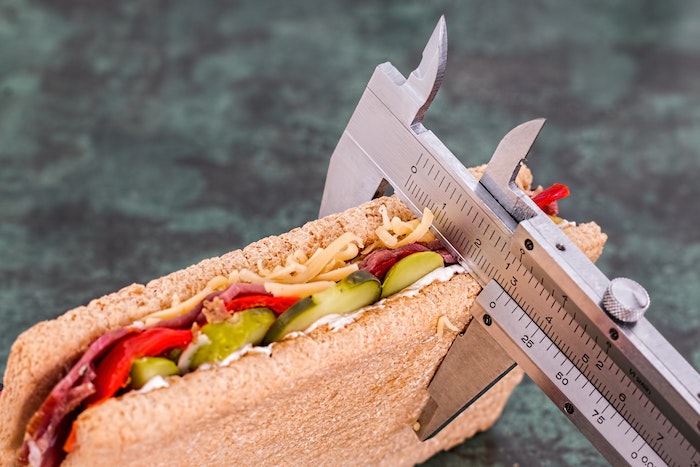 sandwich with bread, pickles, and peppers with body fat measurement tool