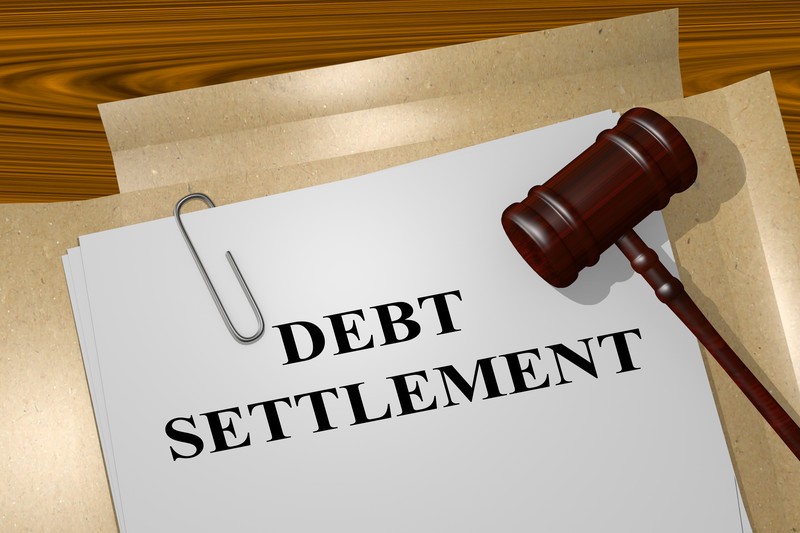 This photo shows a set of legal documents entitled 'Debt Settlement' on a wooden table, underneath a dark wooden gavel, representing the best debt settlement affiliate programs.