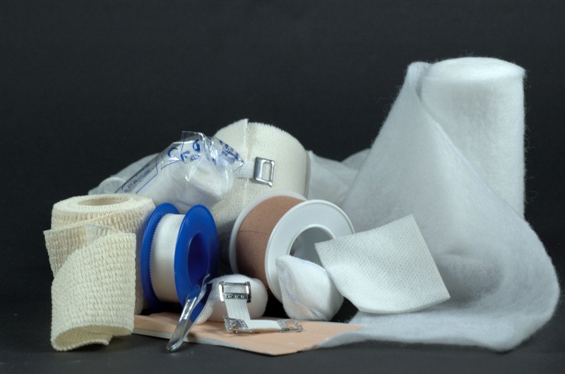 This image shows several packages of bandages, medical tape, gauze, and other medical supplies in a pile against a dark background, representing the best medical supply affiliate programs.