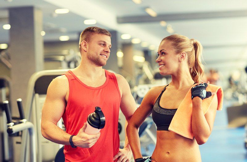 A fit man and woman at the gym with protein shakes