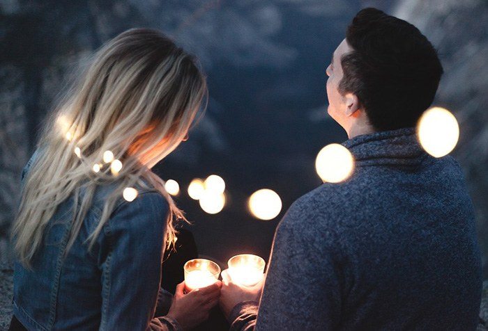 A young man and woman sitting outside with lights all around them