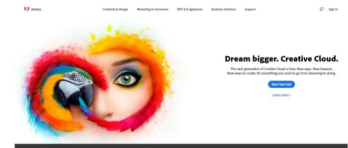 This screenshot of the home page for Adobe has a white background with black text inviting readers to dream bigger, along with a multicolored image of a parrot in front of the face of a woman wearing blue, green, and yellow eye shadow.