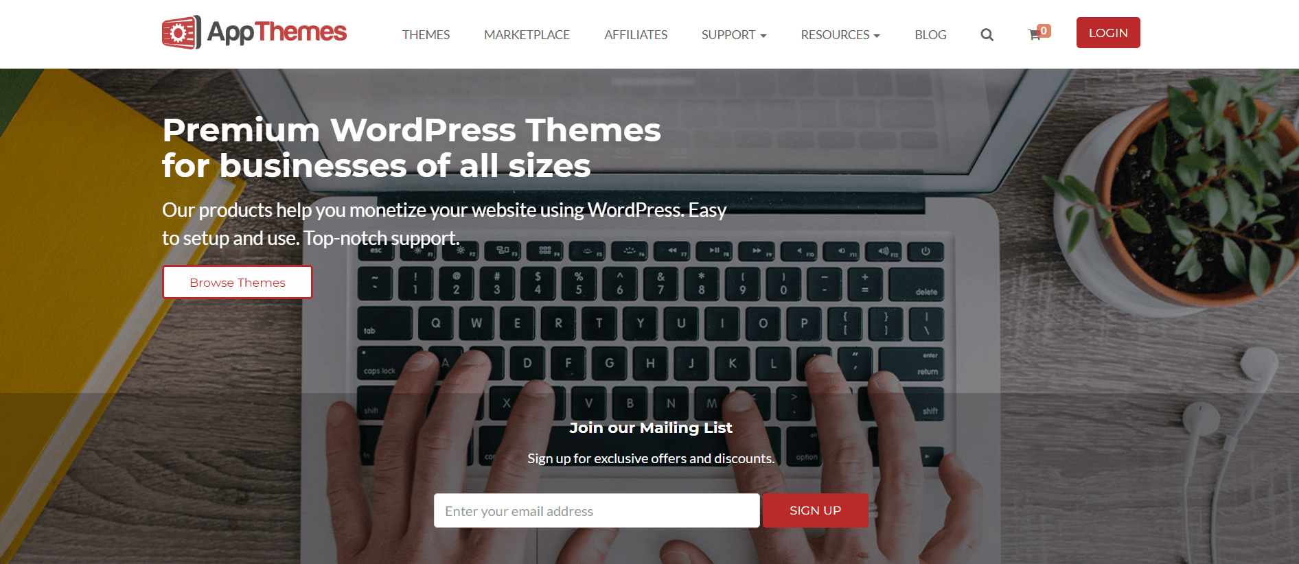 This screenshot of the home page for App Themes has a white navigation bar above an overhead photo of a laptop with hands on the keyboard, behind white lettering announcing premium WordPress themes.