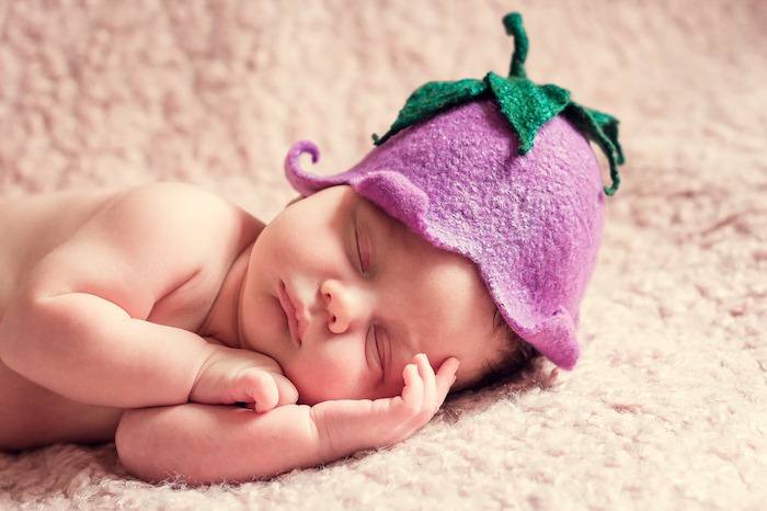 A newborn baby posed with a felt flower hat