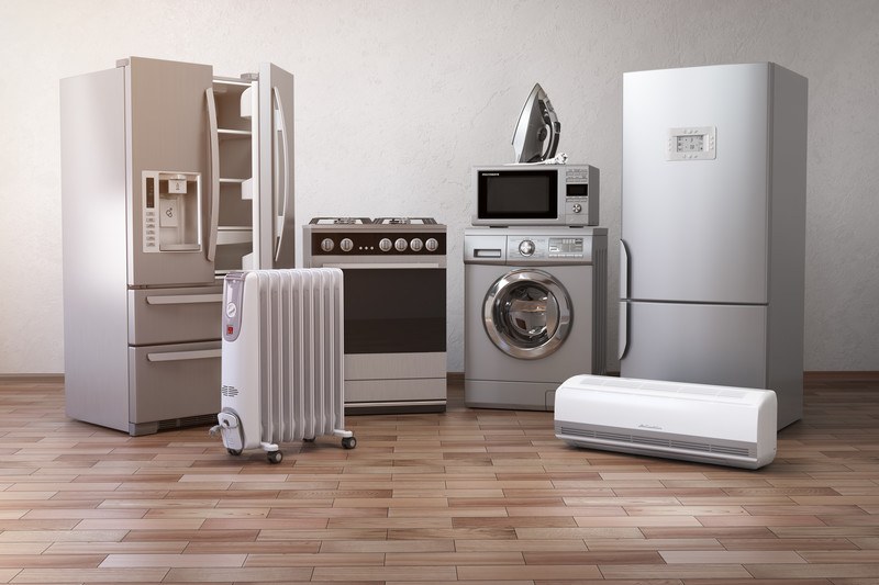 This image showsa row of stainless steel and white appliances, including a refrigerator, a stove, a microwave, a front loading washer, and more in a room with white walls and a brown tile floor, representing the best appliance affiliate programs.