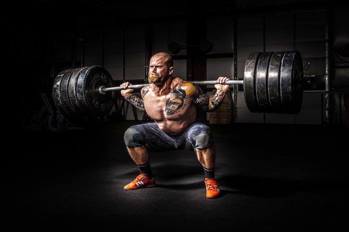 A muscle-bound man lifting a heavy set of weights