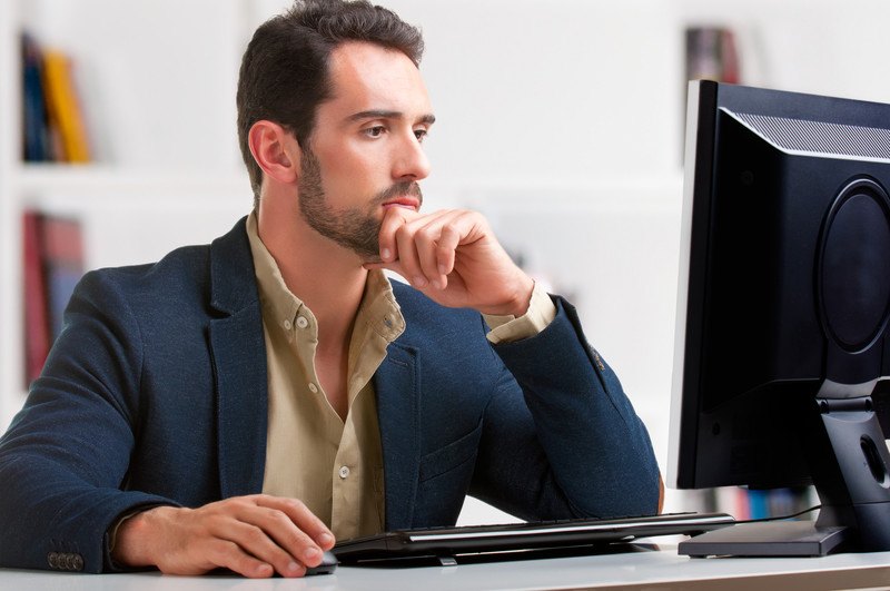 A man in a business suit sitting at his computer