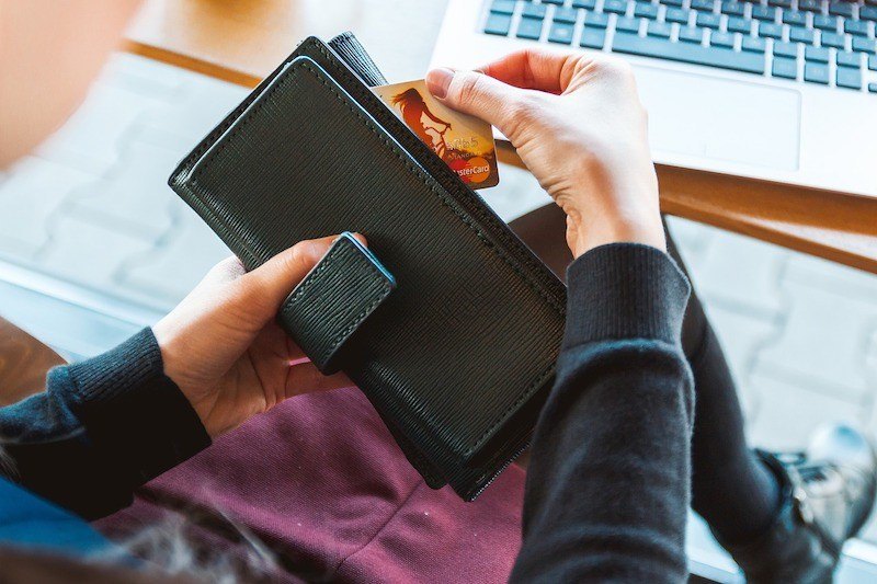 A woman pulling her credit card out of a wallet