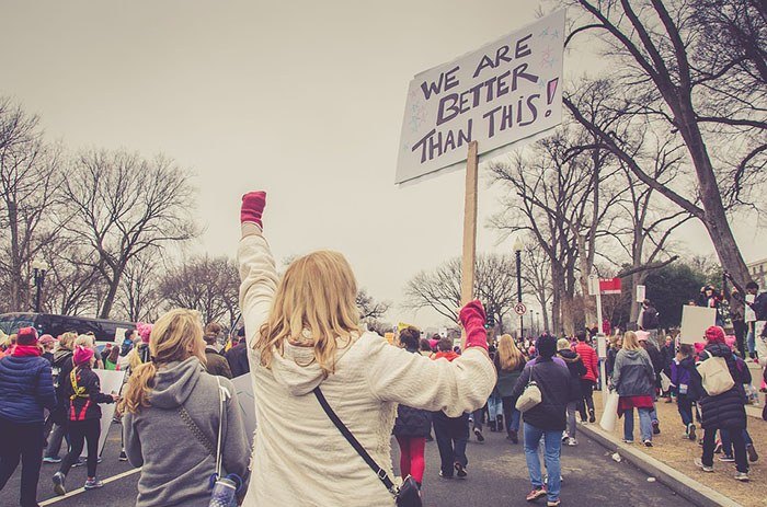 A shot of a group of protestors including a young woman with a sign