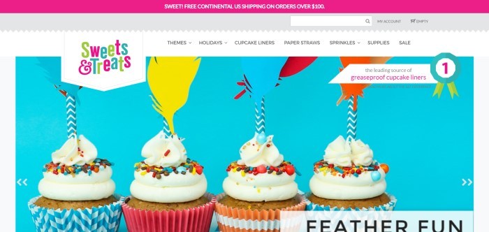 This screenshot of the home page for Sweets & Treats Boutique has a magenta bar at the top announcing free shipping, a white navigation bar, and a main section with a blue background featuring four cupcakes with white frosting and sprinkles in a variety of blue, pink, and orange cupcake liners, with paper feather and straw decorations in blue, yellow, red, and orange.