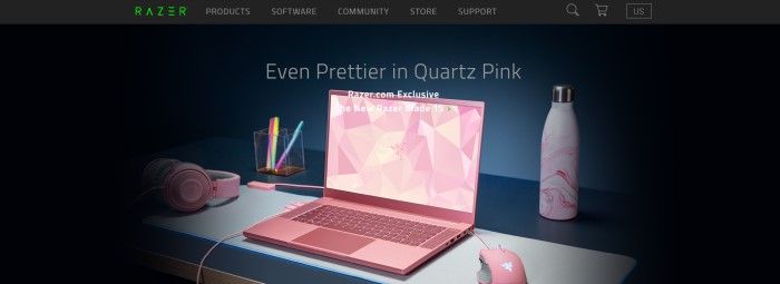 This screenshot of the home page for Razer has a black background with gray text and an image of a quartz-pink Razer Blade 15 laptop, along with a pink mouse, headset, water bottle, and a clear plastic pen holder with multi-colored pens, on a gray and black table. 