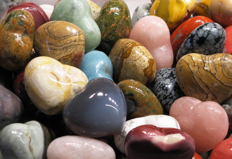 This photo shows a mix of various semiprecious gemstones that have been shaped into hearts and polished, representing the best crystal healing affiliate programs.