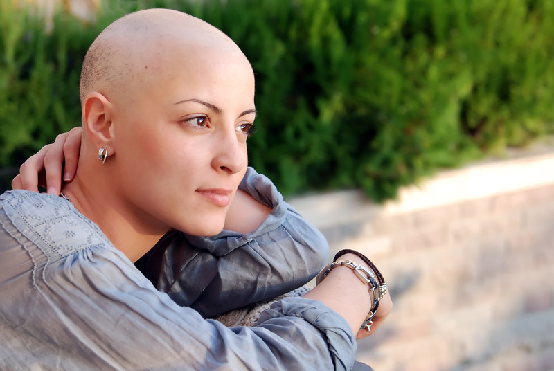 A young cancer patient sitting outside looking content