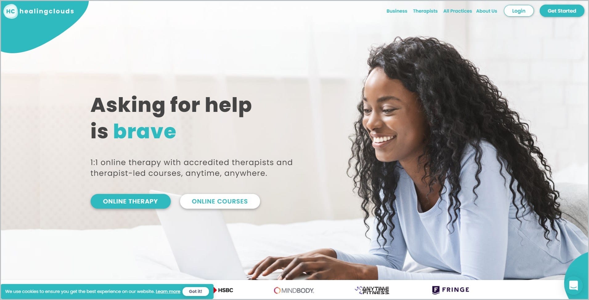 screenshot of HealingClouds homepage with white header with the website's name, and main navigation menu, it showcases a smiling long-haired black woman on her laptop