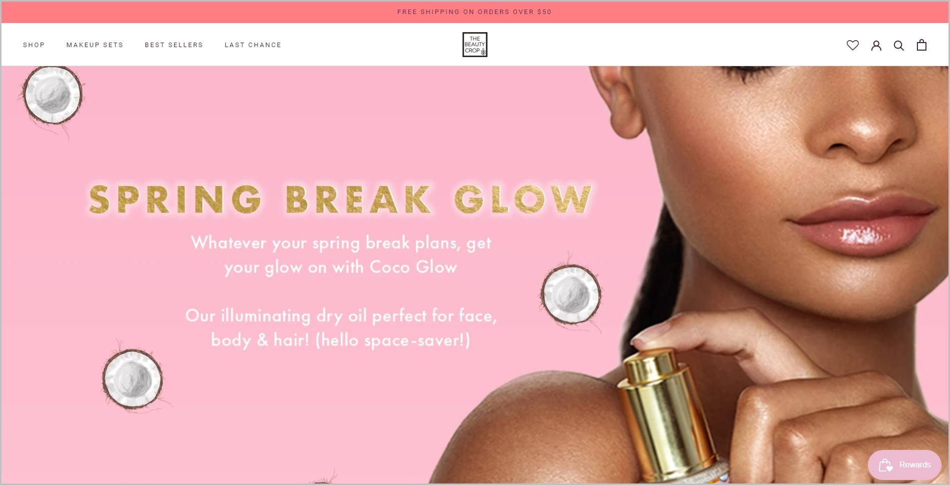 screenshot of The Beauty Crop homepage, with coral announcement bar, white header with the website's name and main navigation menu, it showcases a black woman model holding a skincare product