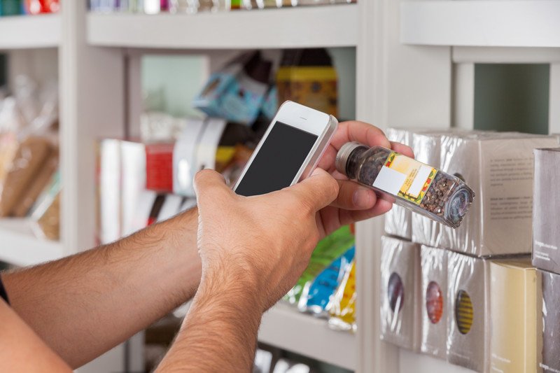 A person using their phone to scan a jar of spice