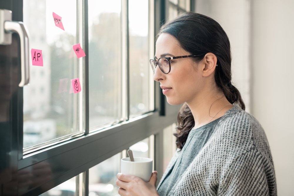 A black haired woman in glasses looking out the window