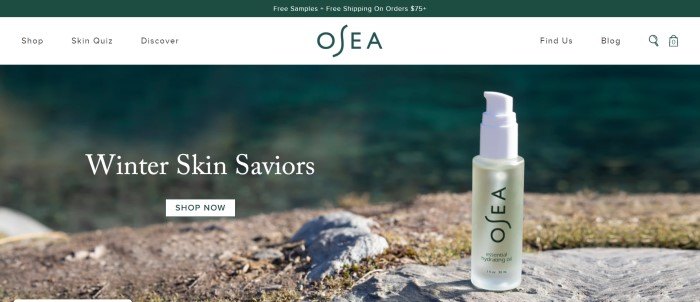 This screenshot of the home page for OSEA has a dark green header and white navigation bar above a large photo showing a bottle of OSEA essential hydrating oil balancing on a rock outdoors, along with white text announcing products to help heal winter skin.