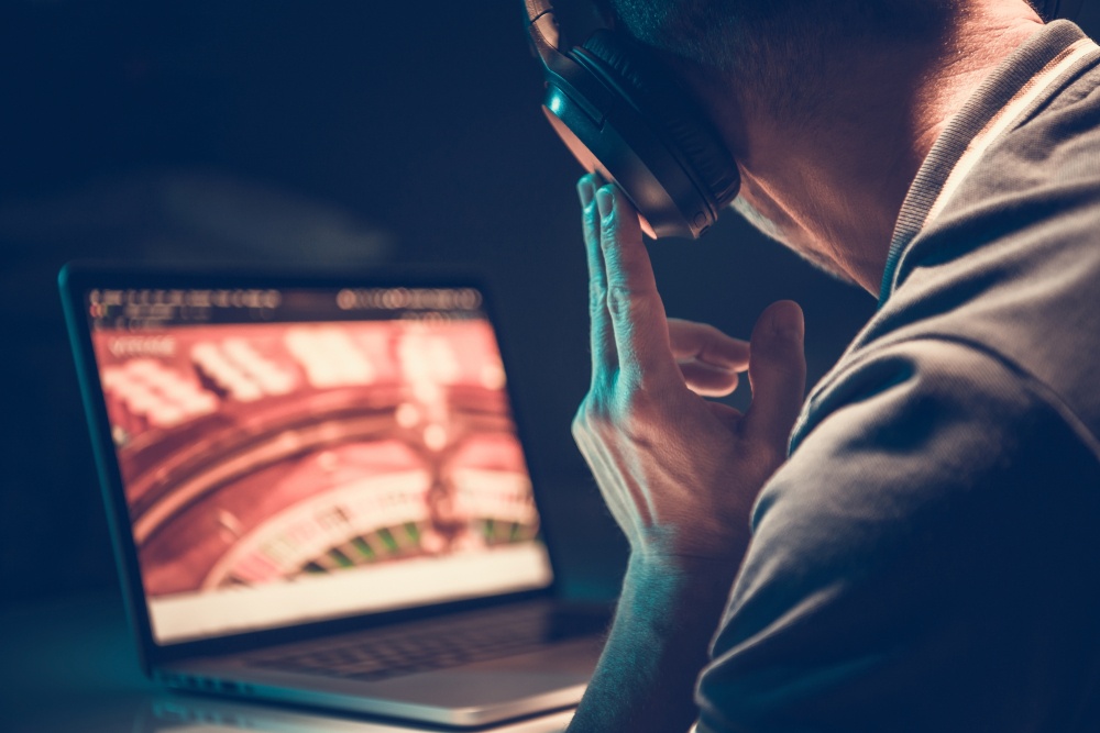 A man sitting in the dark listening to music wearing his headphones