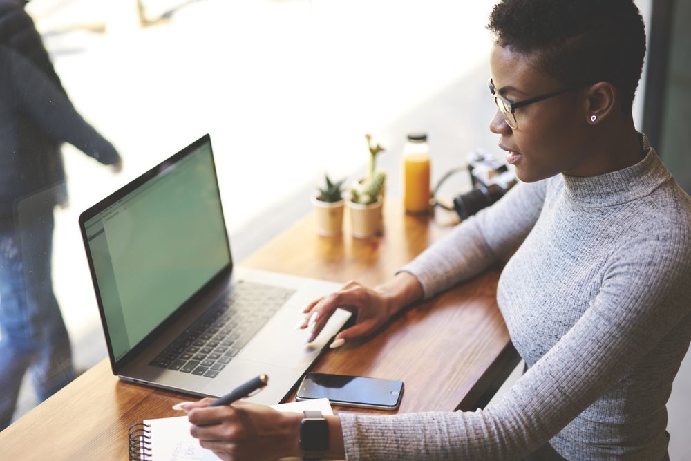 A young woman sitting at a cafe using her laptop to earn