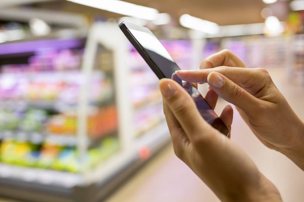 A young woman using a cellphone in the supermarket