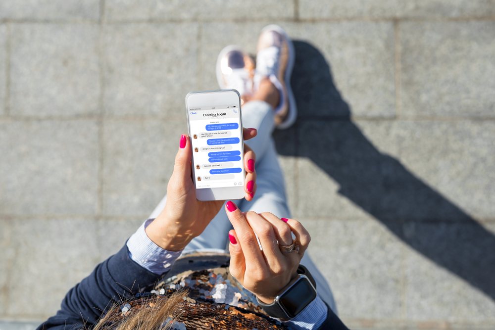 A young woman using a messaging app on her phone