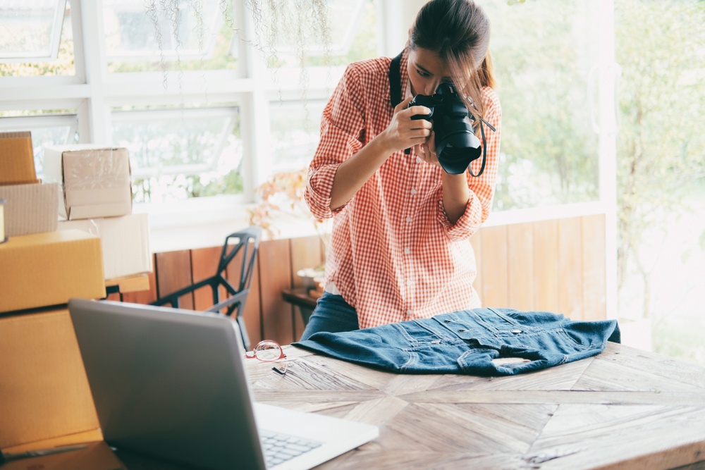 A young woman taking photos of clothese in her house