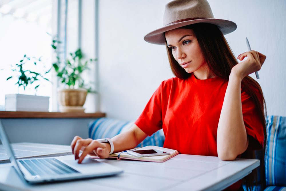 Woman in a red shirt and hat working online