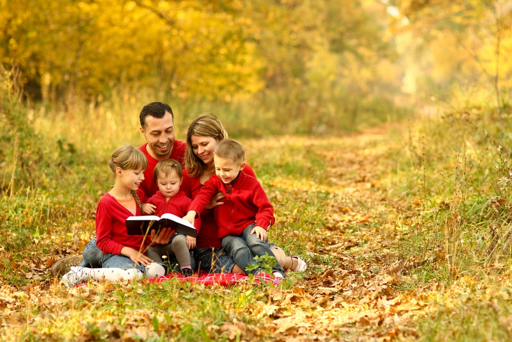 christian family photo in forest reading bible with matching red shirts