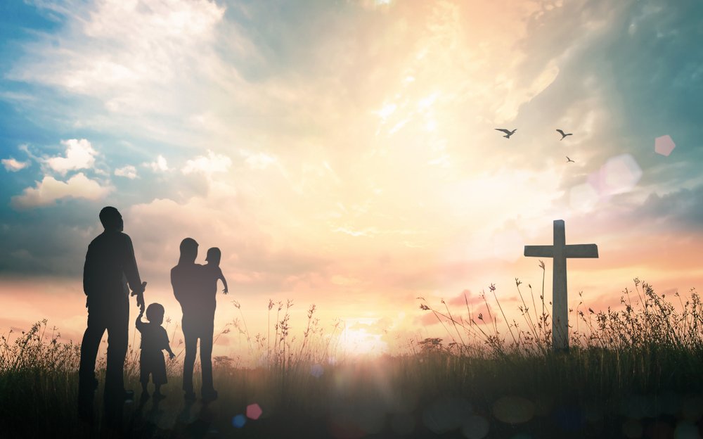 christian family with young children worshiping at the cross