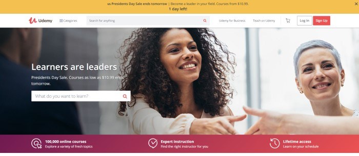 This screenshot of the home page for Udemy has a yellow header announcing a sale, a white navigation and search bar, and a photo of a group of business people smiling and shaking hands, along with white text reading 'Learners are leaders' and a white search bar.