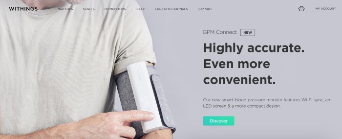 This screenshot of the home page for Withings has a transparent header and navigation bar layered over a large photo with a gray background and chin-to-waist view of a man in a white knit shirt with a gray and white blood pressure monitor on his upper left arm, along with black text on the right side of the page describing the blood pressure device.