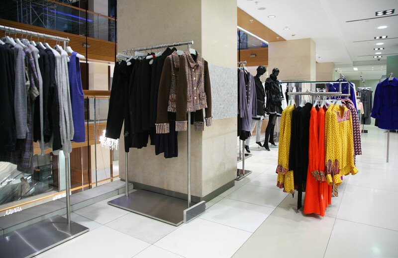 This photo shows a corner of a department store containing women's clothing in black, brown, red, and yellow, representing the best department store affiliate programs.