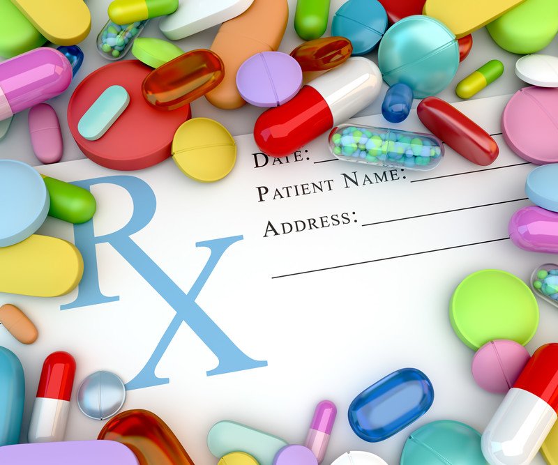 This photo shows an unfilled prescription paper surrounded by several types of pills in many colors, representing the best prescription drug affiliate programs.