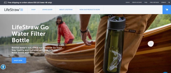 This screenshot of the home page for LifeStraw has a dark header with white text announcing free shipping above a white navigation bar with blue text and a large photo showing a man's hip with a LifeStraw hanging from it as he helps a smiling bearded man in a red jacket and a beanie carry a rowboat down the shore toward a mountain lake, along with a blue call to action button.