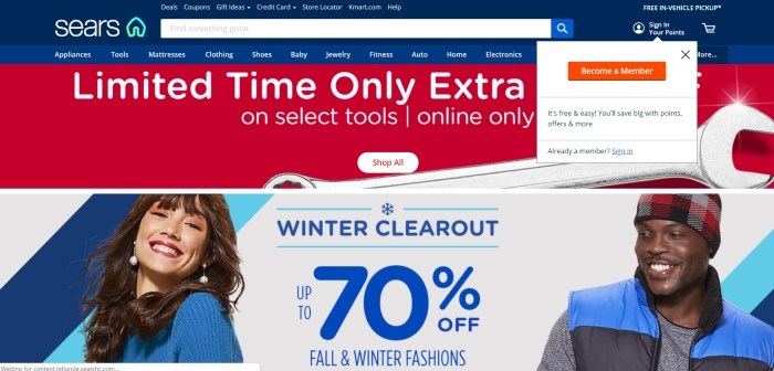 This screenshot of the home page for Sears has a dark blue navigation bar and search bar, a lighter blue secondary navigation bar, a white drop-down box inviting customers to become a member, a red section with white text announcing a limited time deal, and a photo of a smiling dark haired woman in a blue sweater standing near a smiling dark-skinned man in a black and red hat and blue jacket, as well as a white section with blue text announcing a 70% off sale. 