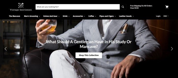 This screenshot of the home page for The Vintage Gentlemen has a dark header and navigation bar with white lettering above a photo of a man from the neck down, dressed in a gray suit with a cigar in the pocket, sitting in what appears to be a leather chair in a luxurious mancave, with glass of whiskey in his hand.