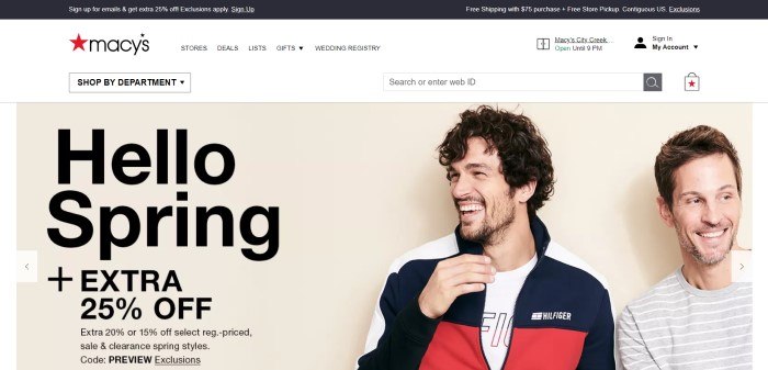 This screenshot of the home page for Macys has a black header, a white navigation bar, and a photo of two smiling men in fashion clothing--one in a white, black, and red jacket and the other in a gray and white striped shirt--next to black text announcing a spring sale. 