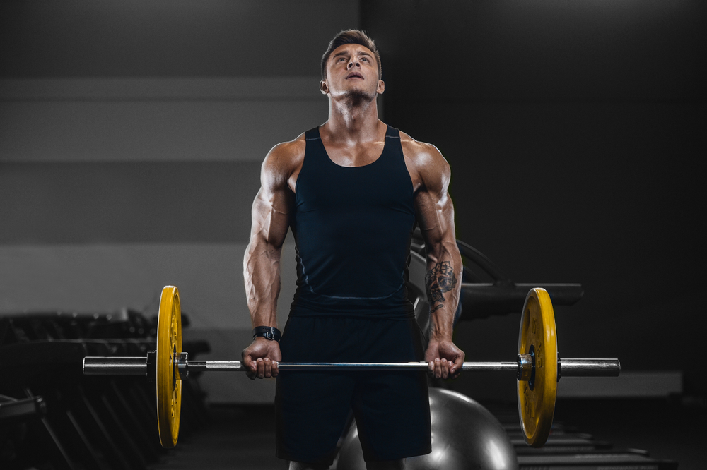 young man doing curls with bar bell doing bodybuilding