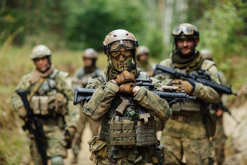 Best Airsoft Affiliate Programs | One More Cup of Coffee This image shows a group of five men wearing tactical gear and carrying guns in a wooded area, representing the best airsoft affiliate programs.