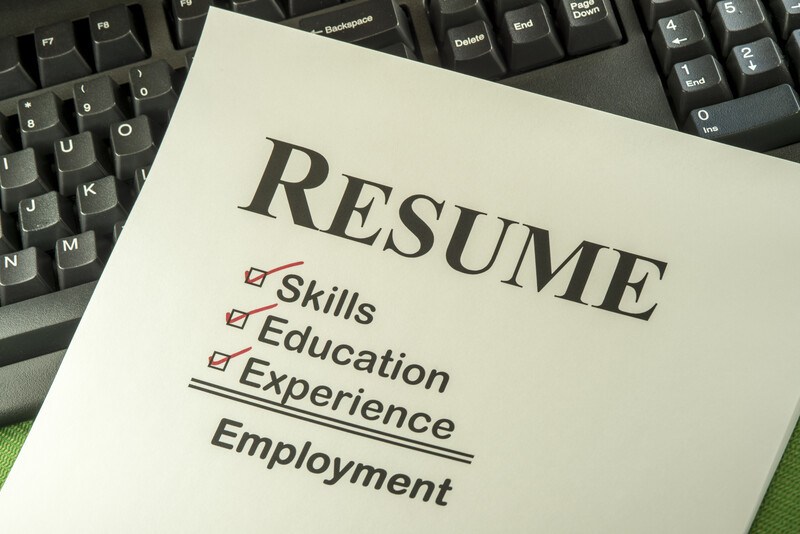 This photo shows a pale yellow resume template lying across a computer keyboard, representing the best resume affiliate programs.