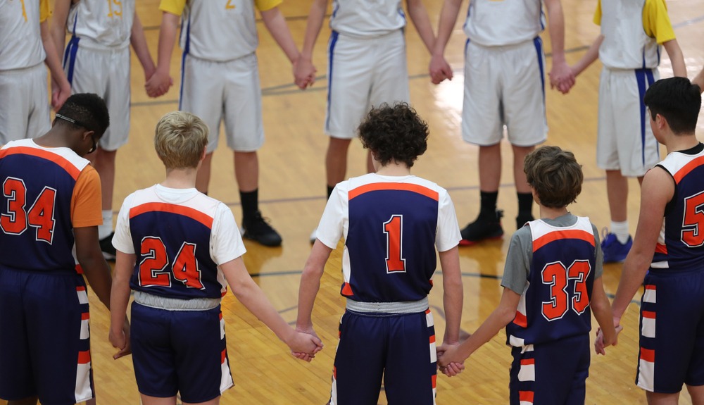 Christian Youth basketball team holding hands before game