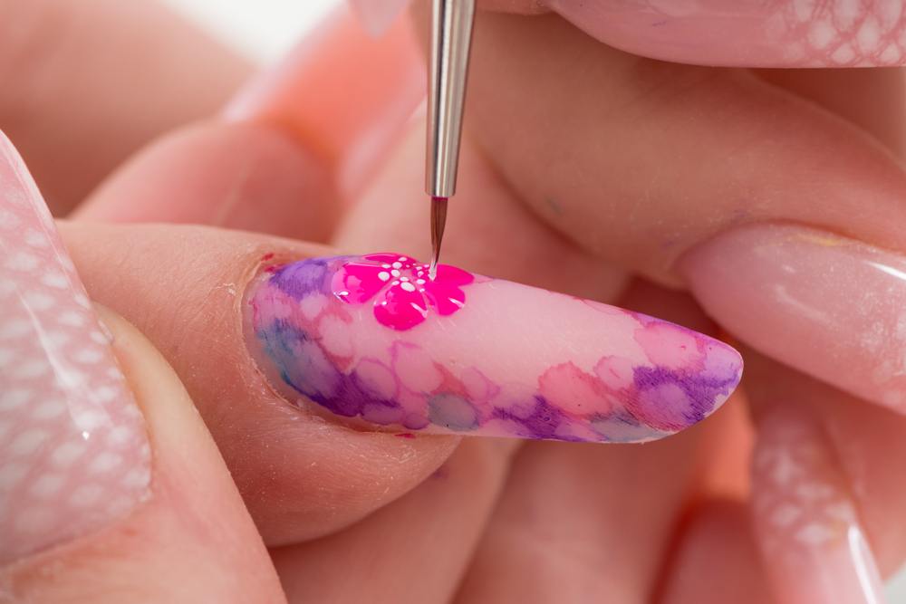 close up photo of paining flower on long fingernail