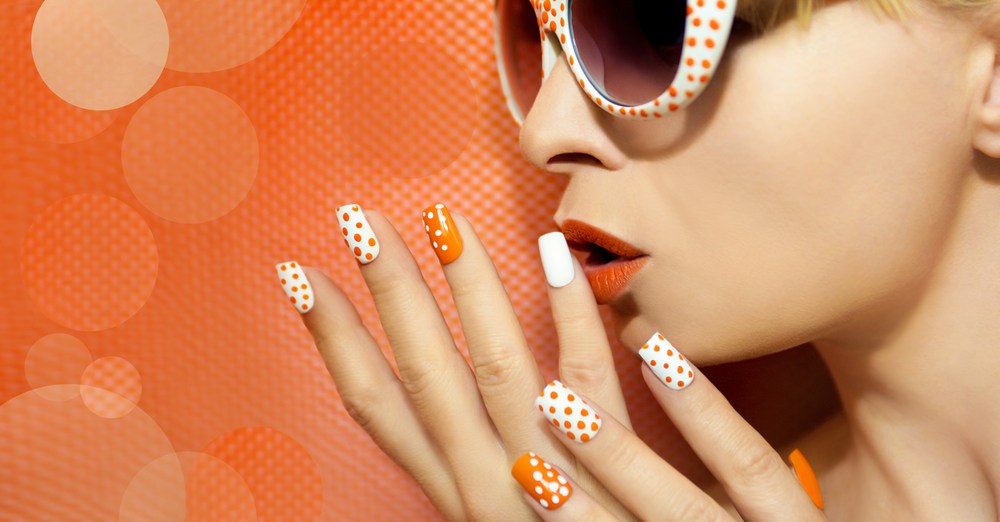 fashionable woman with orange polka dot nail art and sunglasses