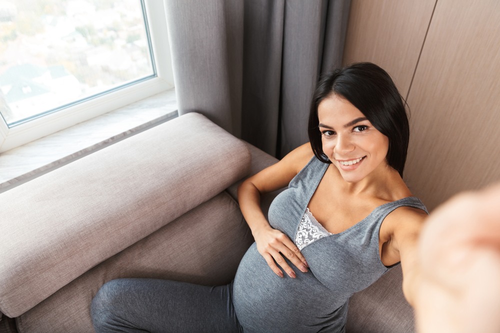 latina pregnant mom taking selfie with camera